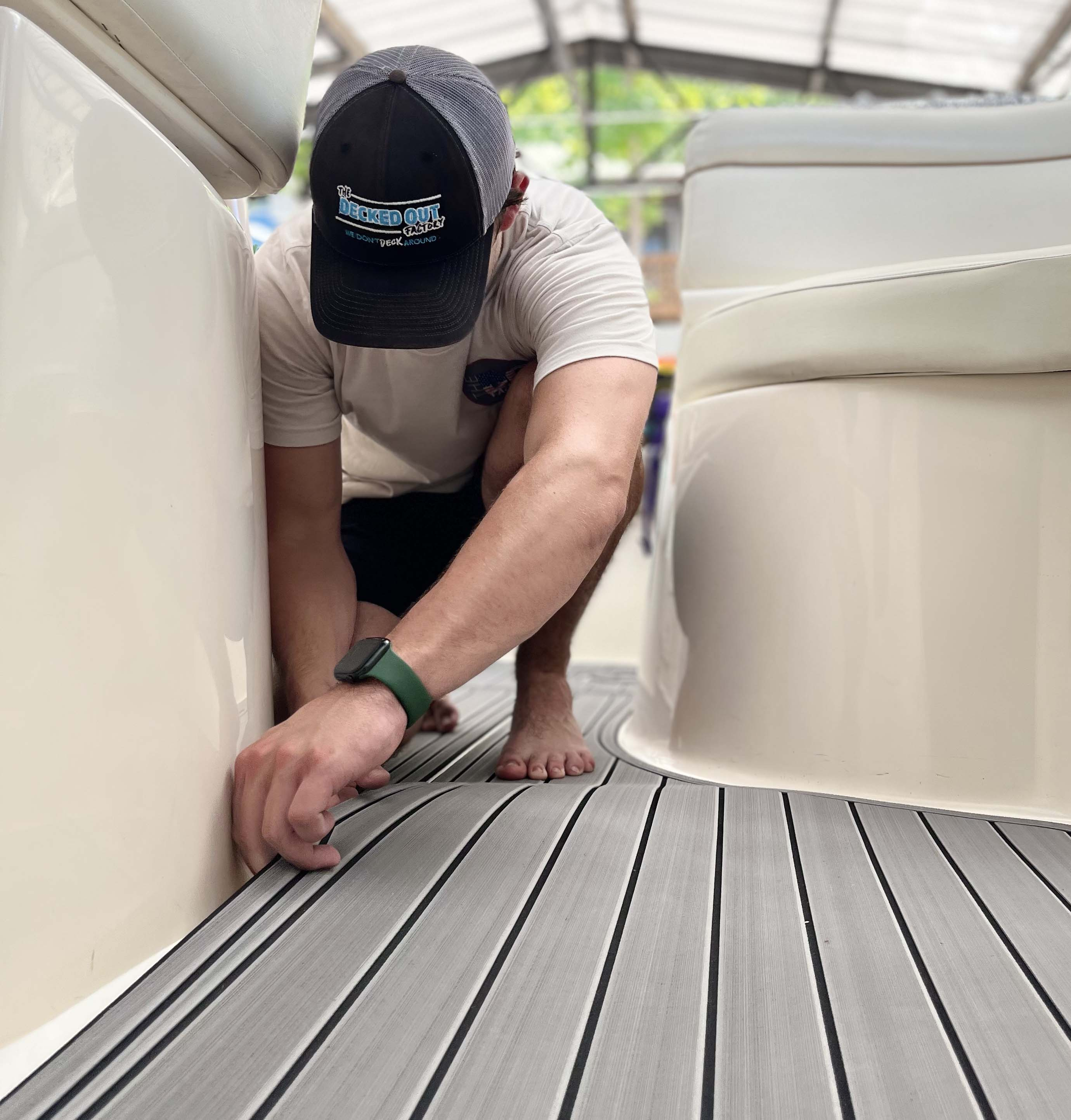 A man carefully installing a large piece of EVA foam flooring onto a boat deck.